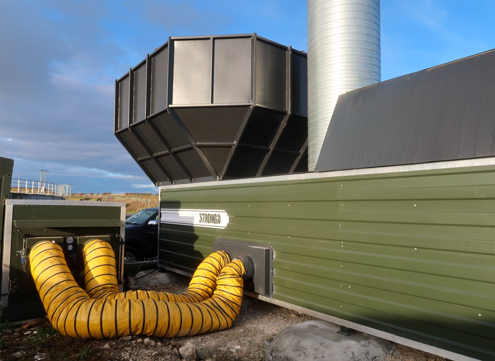 FlowDrya manure dryer with yellow heat ducts using residual heat from poultry houses