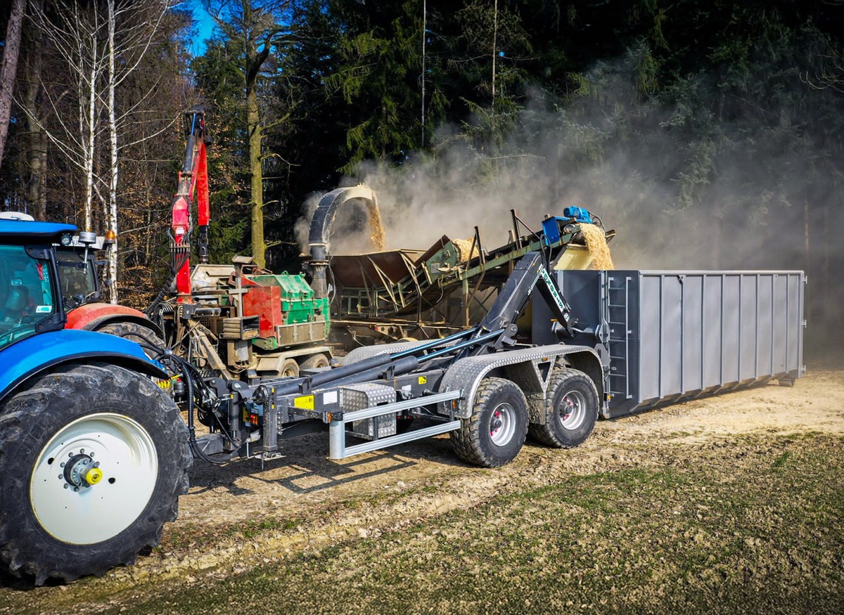 Chipping green wood into ground-demounted container using a Stronga hook lift trailer, ready for delivery to the flow drying plant
